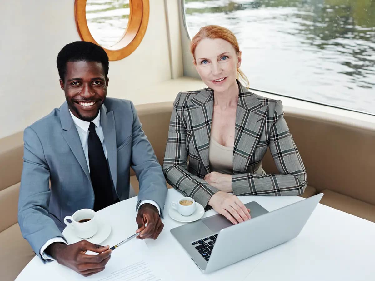 Two business partners at a table with a laptop and documents